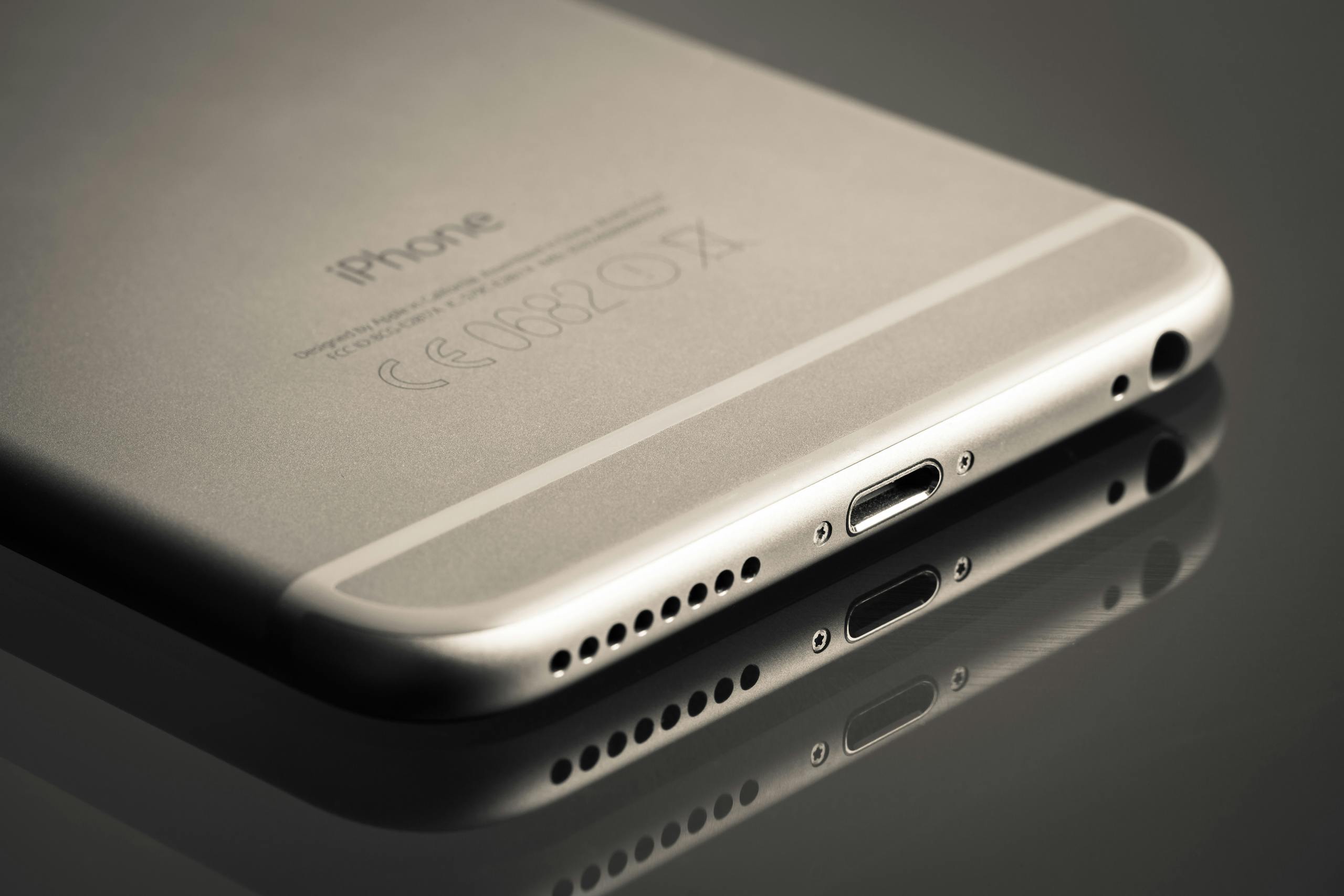 A sleek smartphone displayed at an angle showcasing its reflection on a smooth surface.