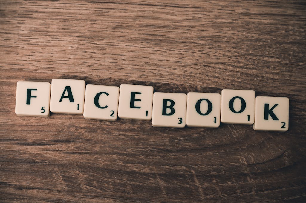 Scrabble tiles spelling 'Facebook' on a wood background, symbolizing social media.
