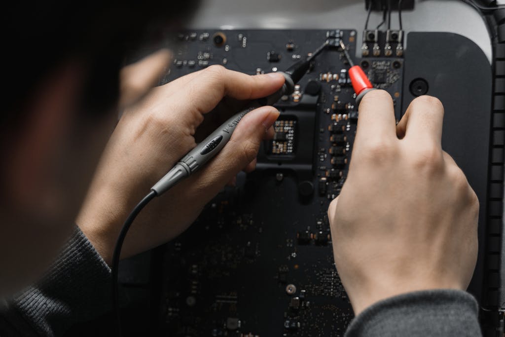 Close-up of hands repairing a circuit board using a soldering iron, emphasizing technical skill.